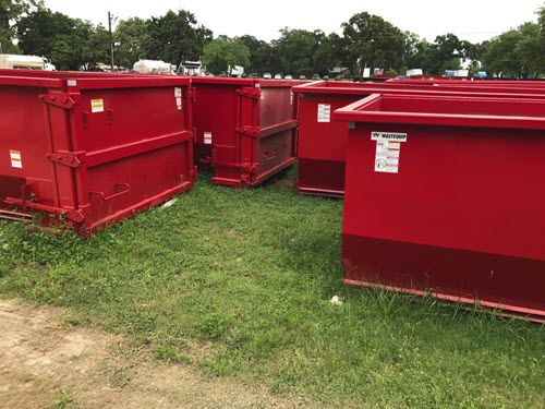 several red dumpsters located in grass